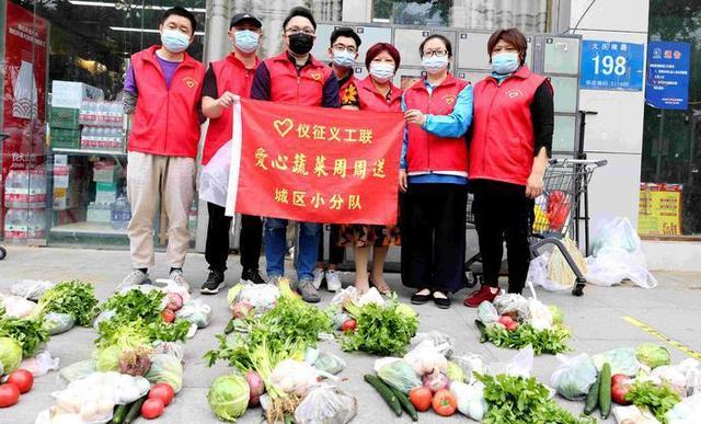 一群身穿红马甲的仪征市义工联义工,正在采购"蔬菜周周送敬老公益项目